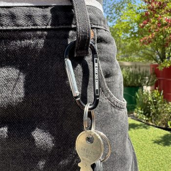 Karabiner mit Schlüsselbund am Hosenbund, Gravur «Be gay. Do crime.»