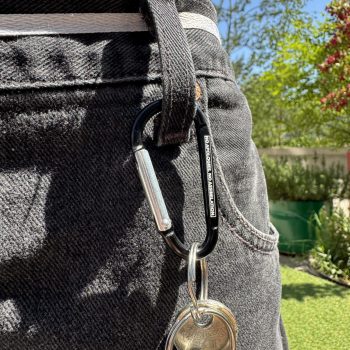 Karabiner mit Schlüsselbund am Hosenbund, Gravur «No apologies. No assimiliation.»