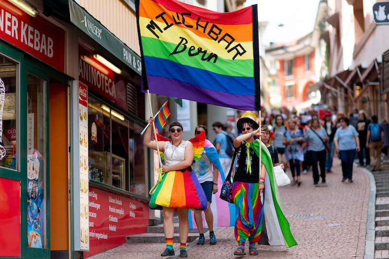 Zwei Queers tragen in der Altstadt ein Banner der Milchbar Bern