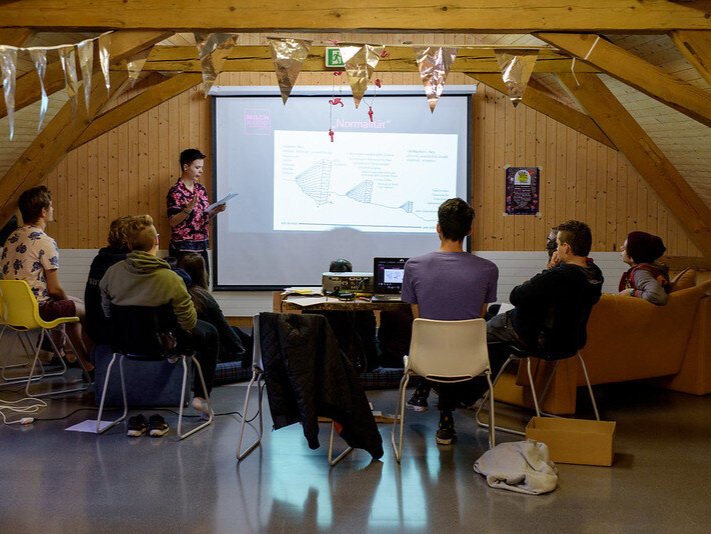 Milchjugend-Aktivist*in hält Vortrag vor einer kleinen Gruppe von Menschen